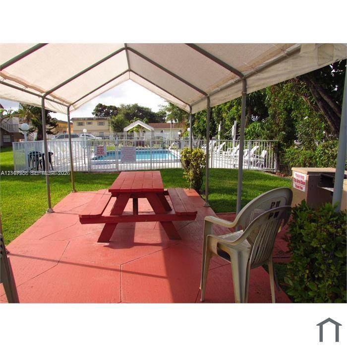 Covered outdoor patio with stamped concrete flooring, fenced swimming pool, and manicured lawn