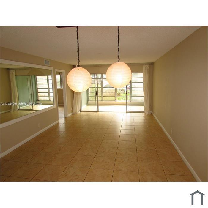 Ceramic tile flooring, dual globe pendant lighting, wall-mounted mirror, and floor-to-ceiling sliding glass doors