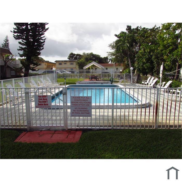 In-ground swimming pool featuring a concrete paver deck and metal perimeter fencing