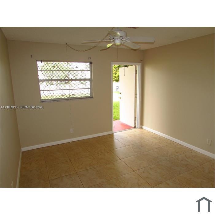 Ceramic tile flooring, ceiling fan with integrated lighting, and window with decorative metal security screening
