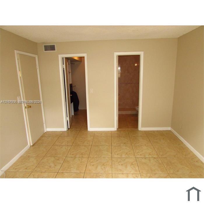 Neutral-toned room featuring large-format ceramic tile flooring, two solid-core interior doors, and built-in closet shelving