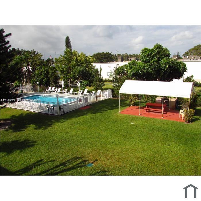 Outdoor area featuring an in-ground swimming pool with perimeter fencing, a covered patio structure, and a lawn