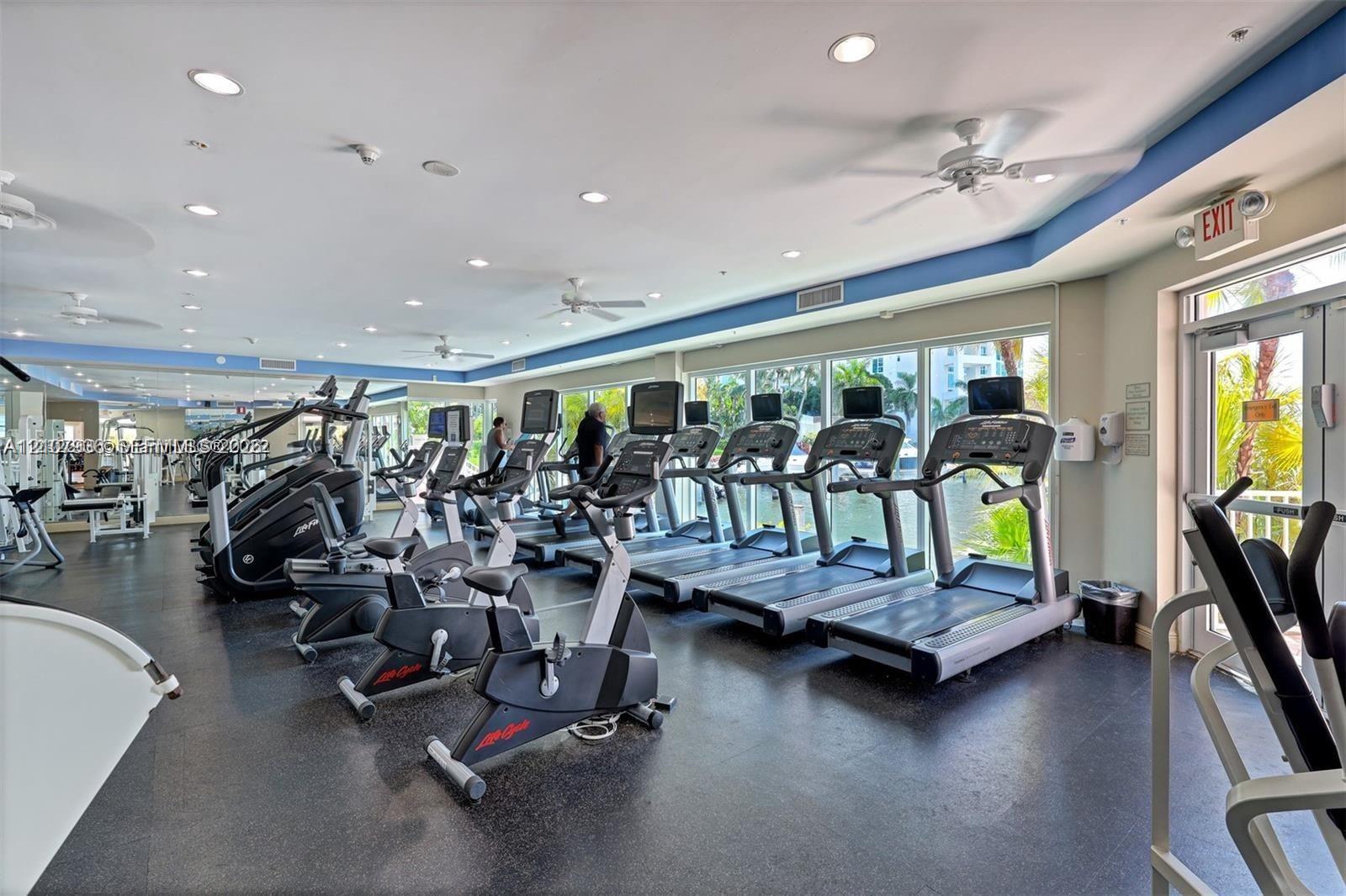 Fitness center featuring rubber flooring, recessed lighting, ceiling fans, mirrored walls, and floor-to-ceiling glass windows