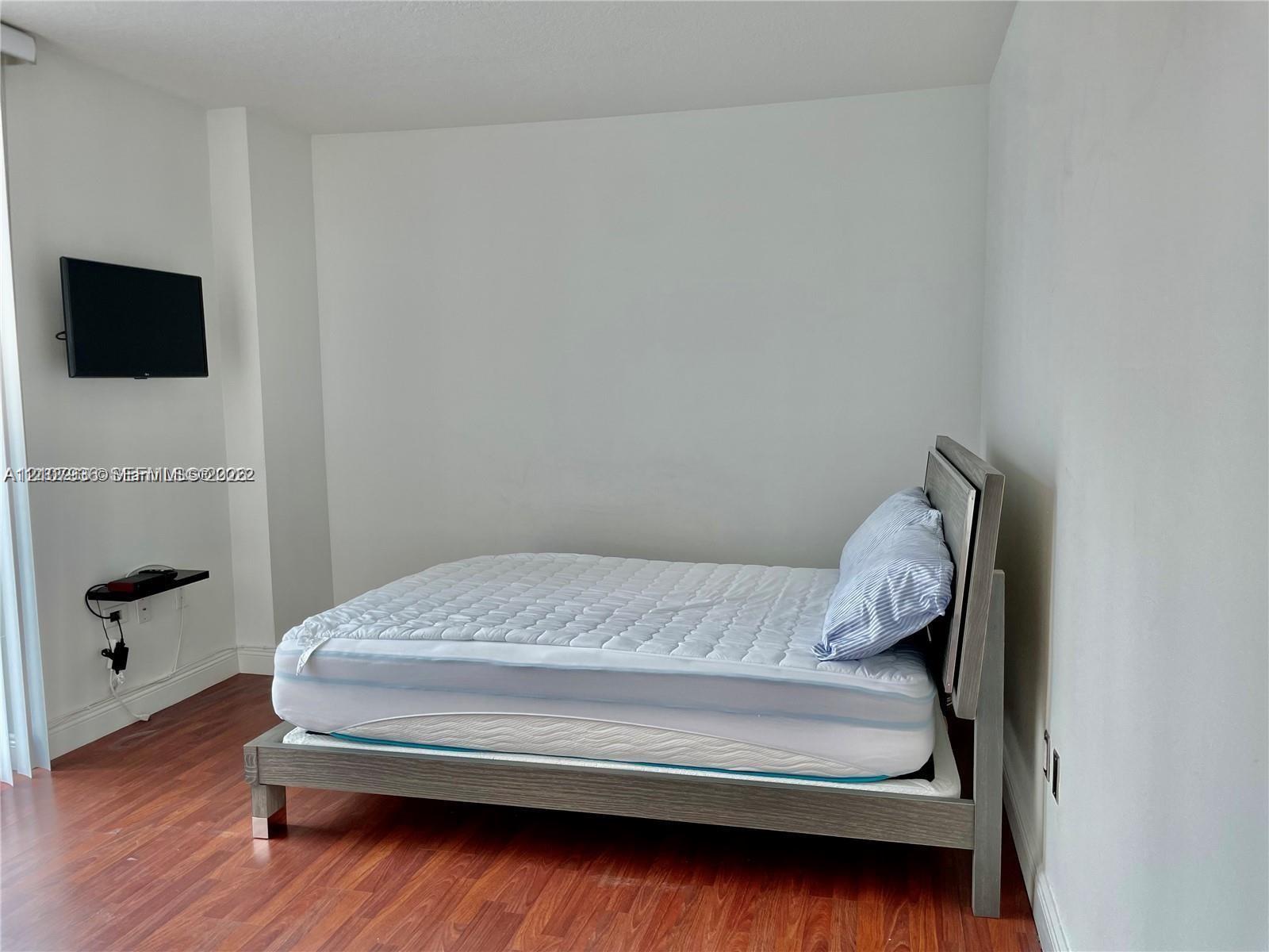 Room featuring wood-finish flooring and wall-mounted shelving