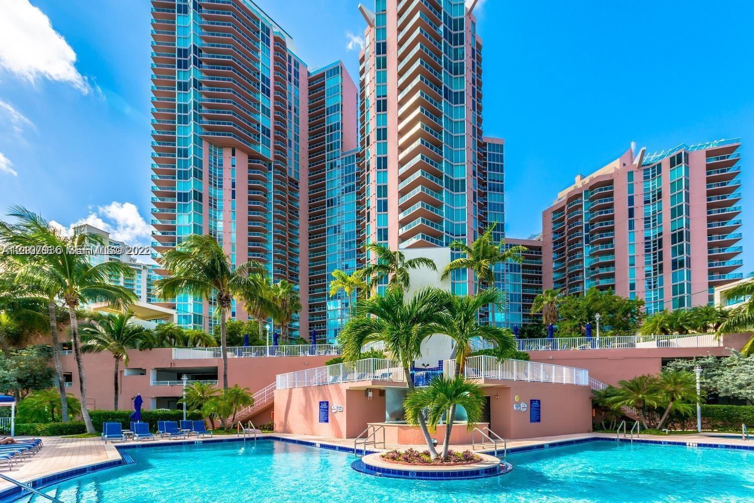 High-rise residential exterior featuring expansive glass balconies, an outdoor swimming pool, integrated landscaping, and a central raised island planter