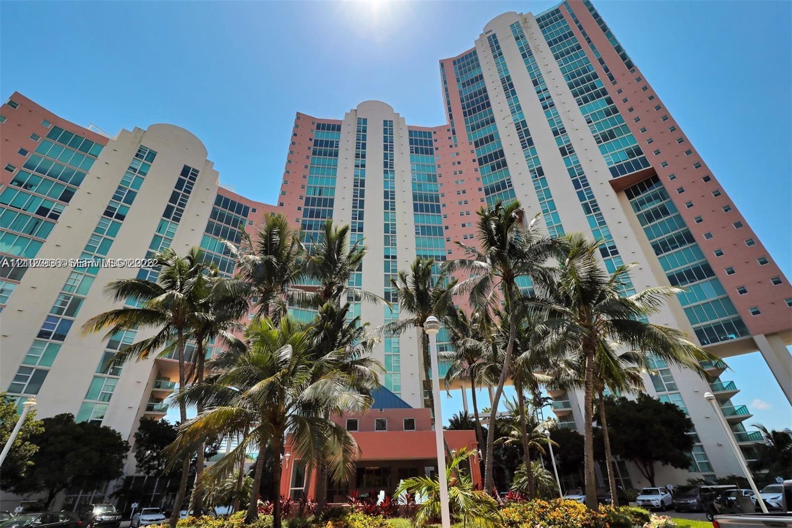 High-rise architectural exterior featuring multi-story glass facade, tiered building design, and expansive glass window installations complemented by manicured palm landscaping