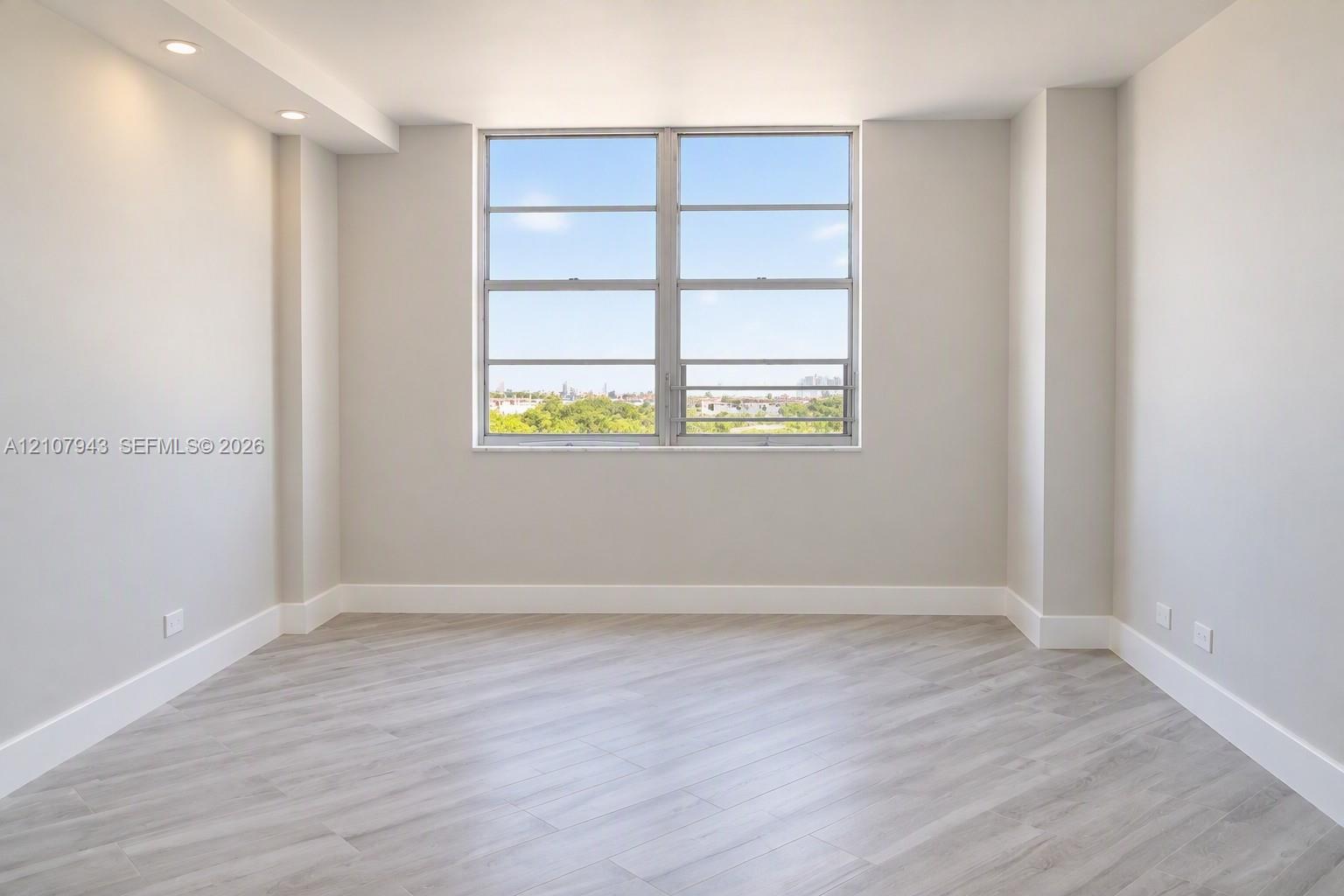 Neutral walls, wood-finish flooring, recessed lighting, and large picture window with outdoor scenery