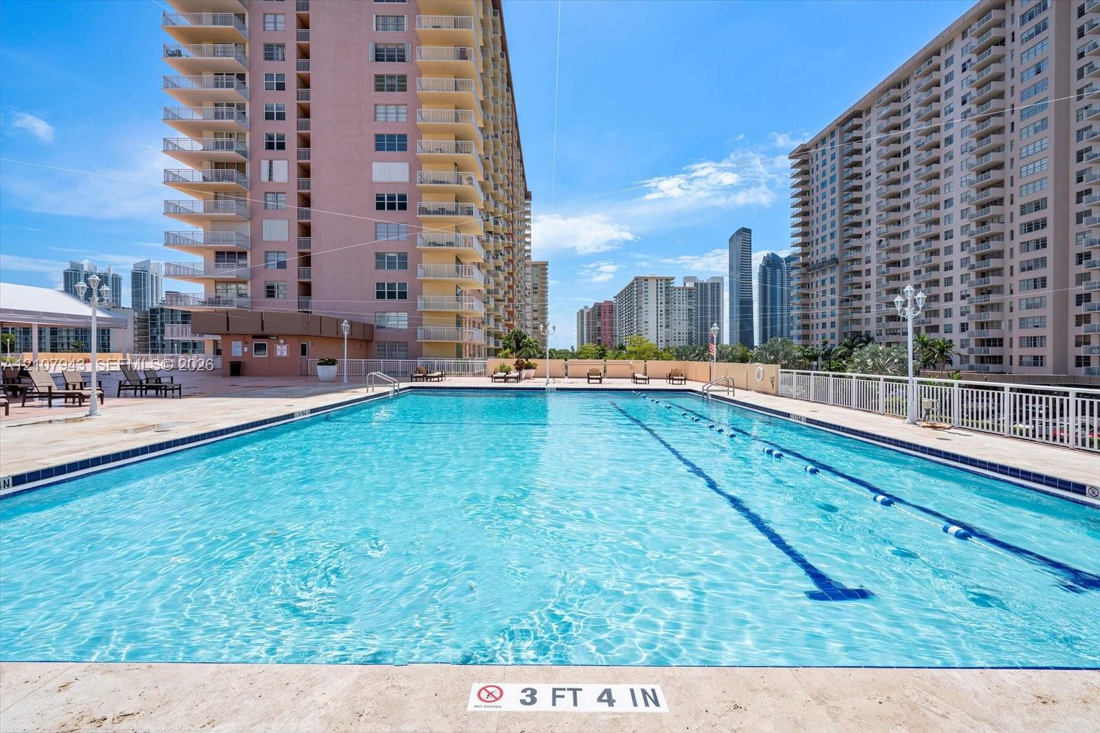 Outdoor swimming pool featuring a lap lane, concrete pool deck, and perimeter metal fencing