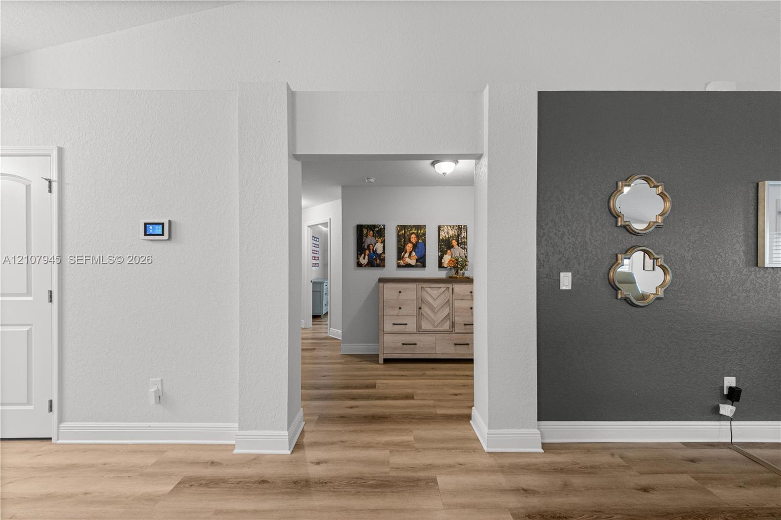 Interior space featuring wide-plank wood-finish flooring, a dark charcoal accent wall, and a central architectural archway