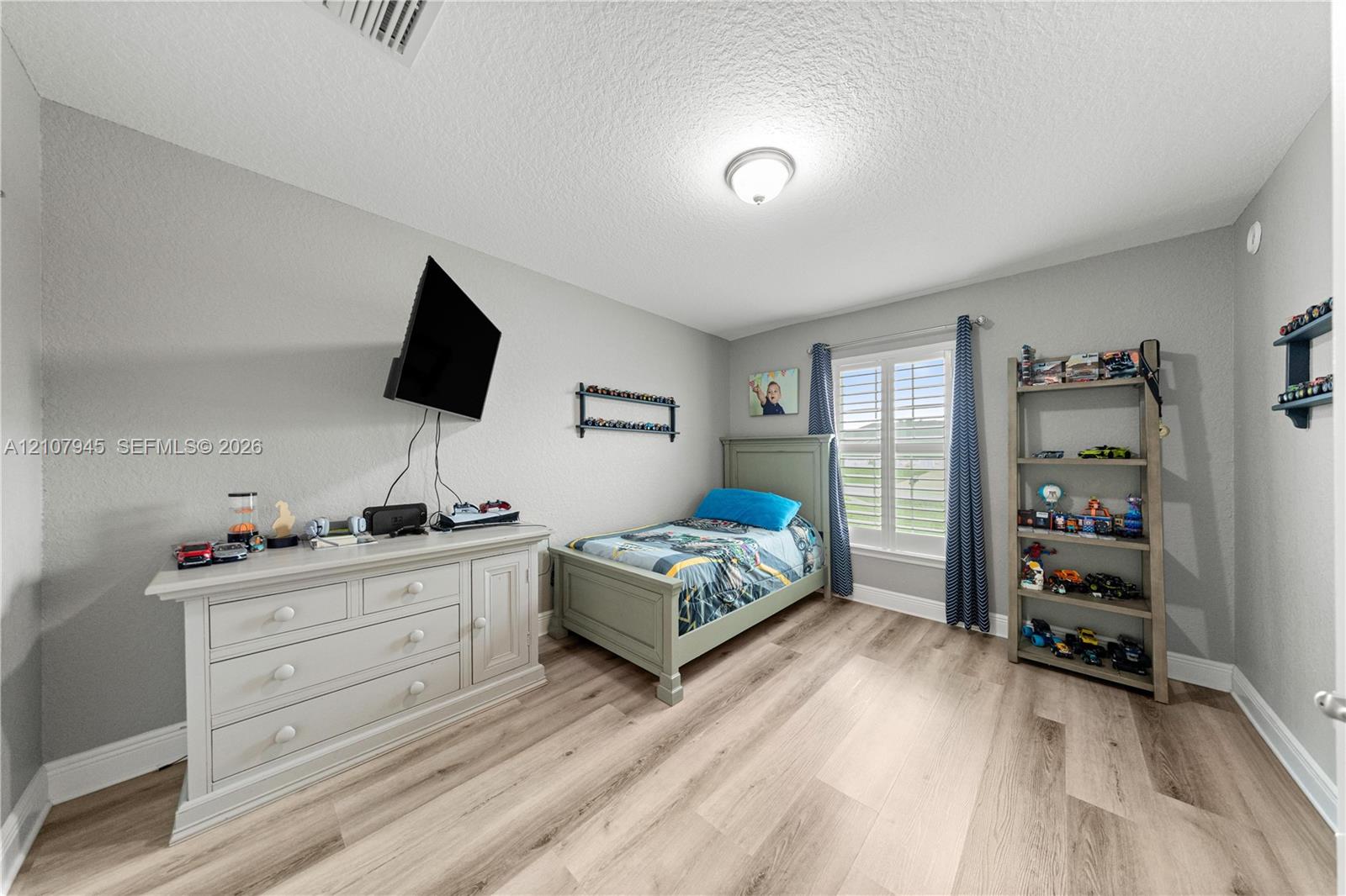 Room featuring neutral-toned walls, wood-finish flooring, and a single window with plantation shutters