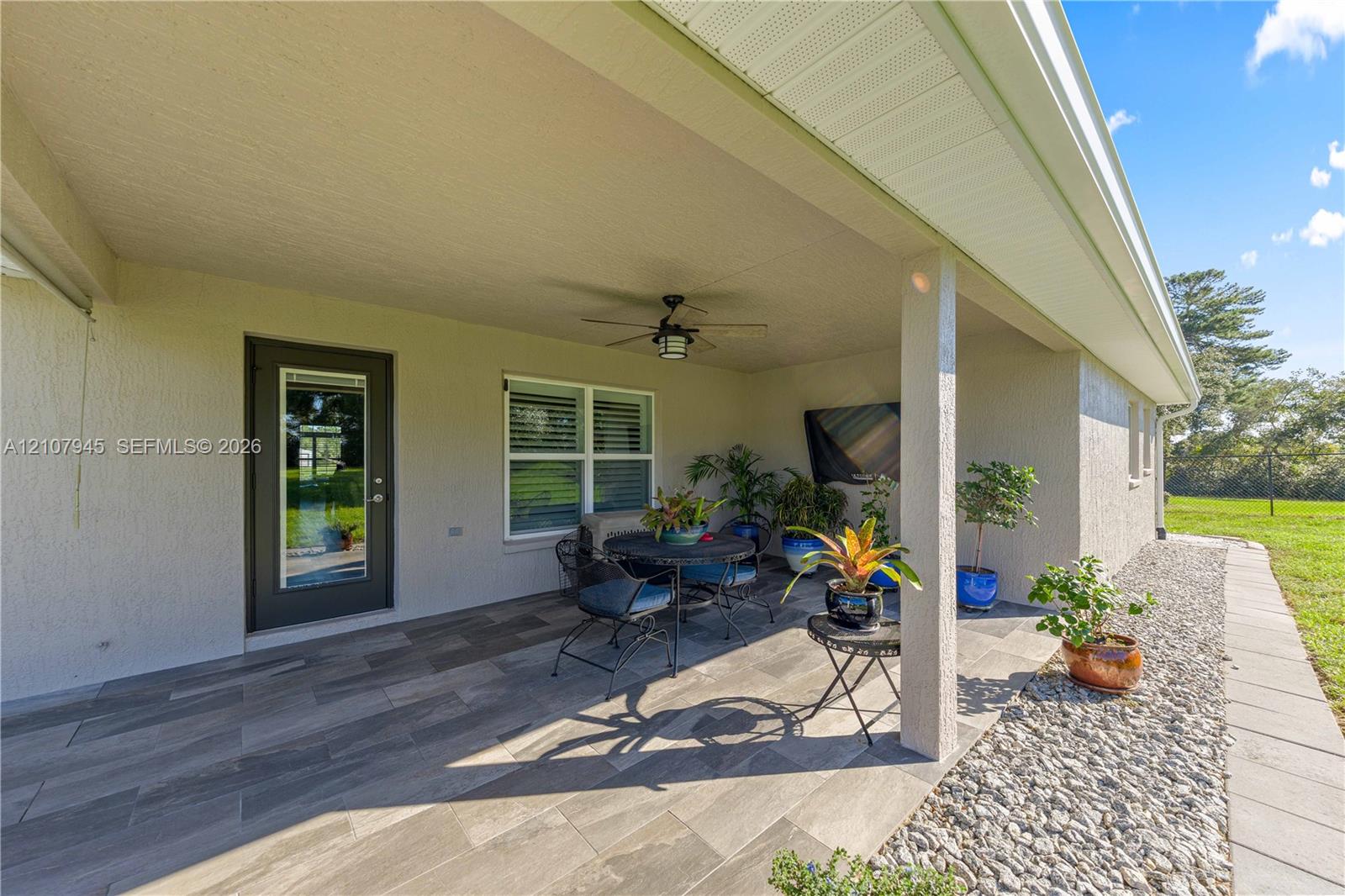 Covered outdoor patio featuring wood-finish tile flooring, a ceiling-mounted fan, and a glass-paneled exterior door