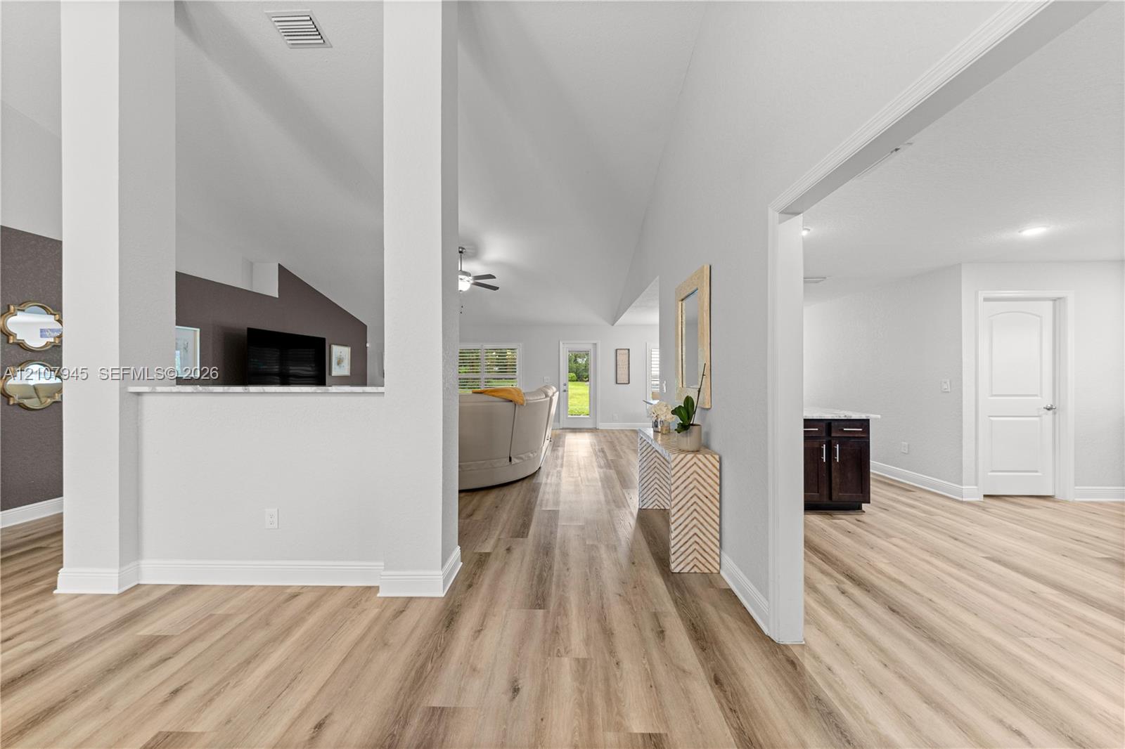 Vaulted ceilings, wood-finish flooring, and a partial architectural wall with a stone-top ledge