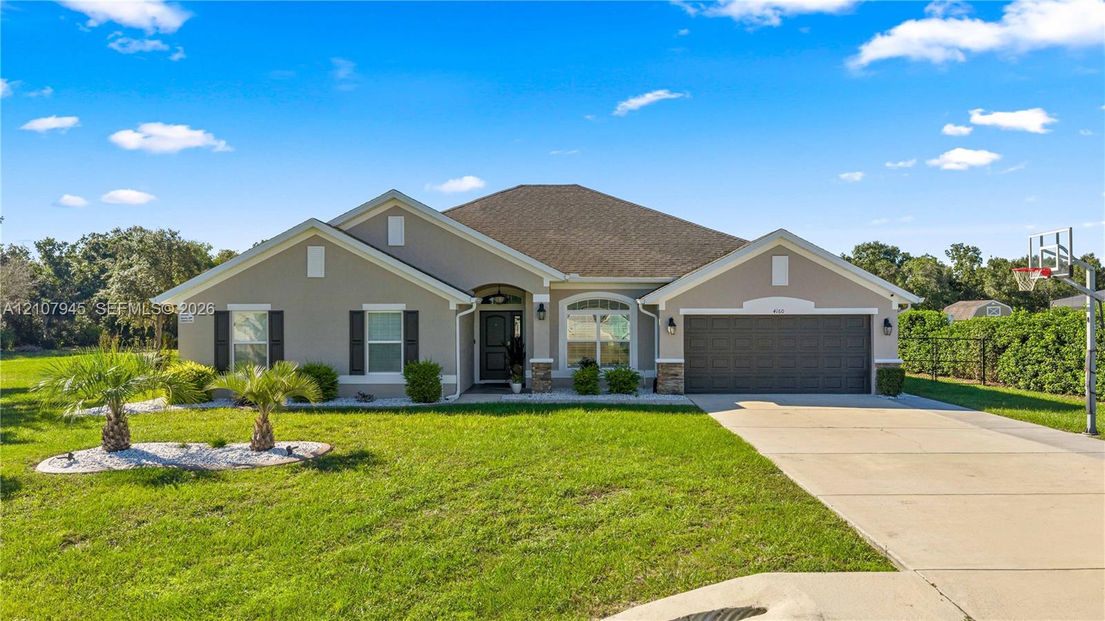 Single-story residence featuring a neutral-toned stucco exterior, decorative window shutters, an arched entryway, and an attached multi-car garage