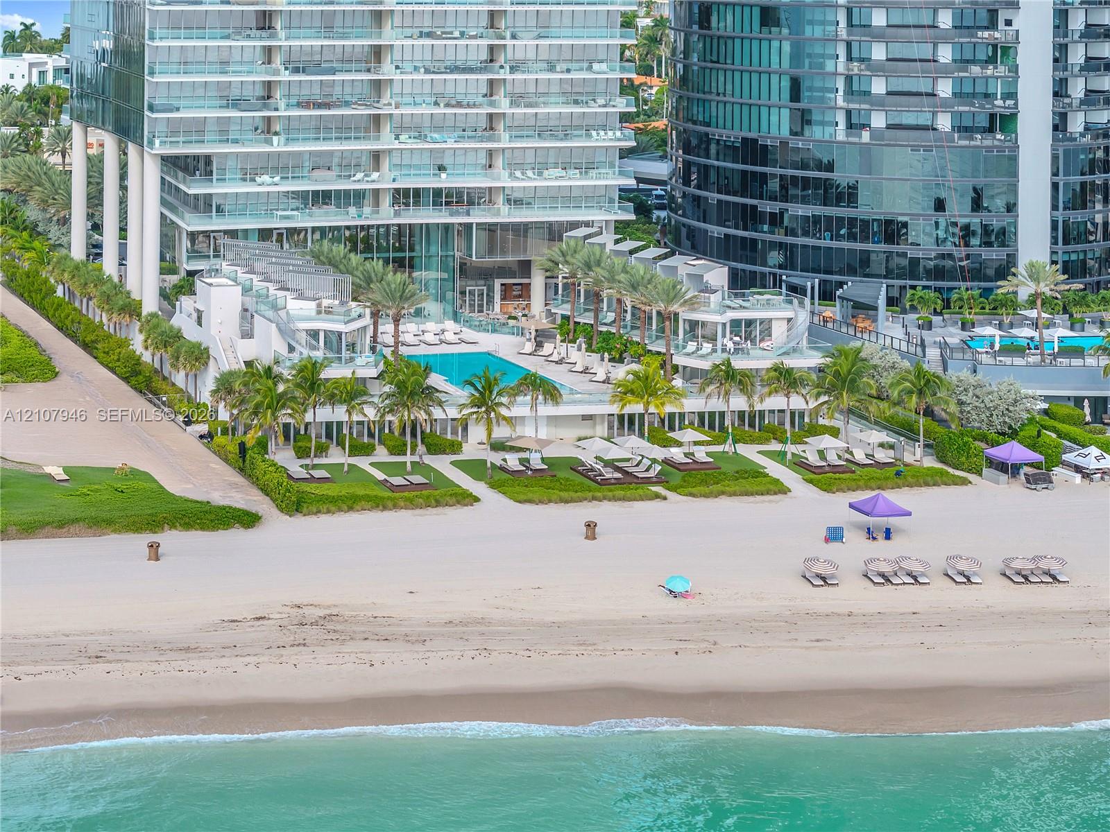 Beachfront high-rise property featuring a multi-level swimming pool, private coastal access, manicured landscaping, and glass-railed terraces Beachfront high-rise property featuring a multi-level swimming pool, private coastal access, manicured landscaping, and glass-railed terraces