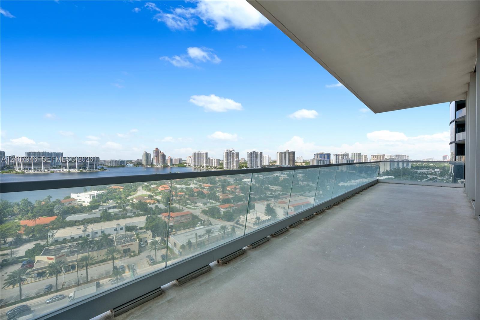 Covered balcony featuring concrete flooring and a transparent glass panel railing