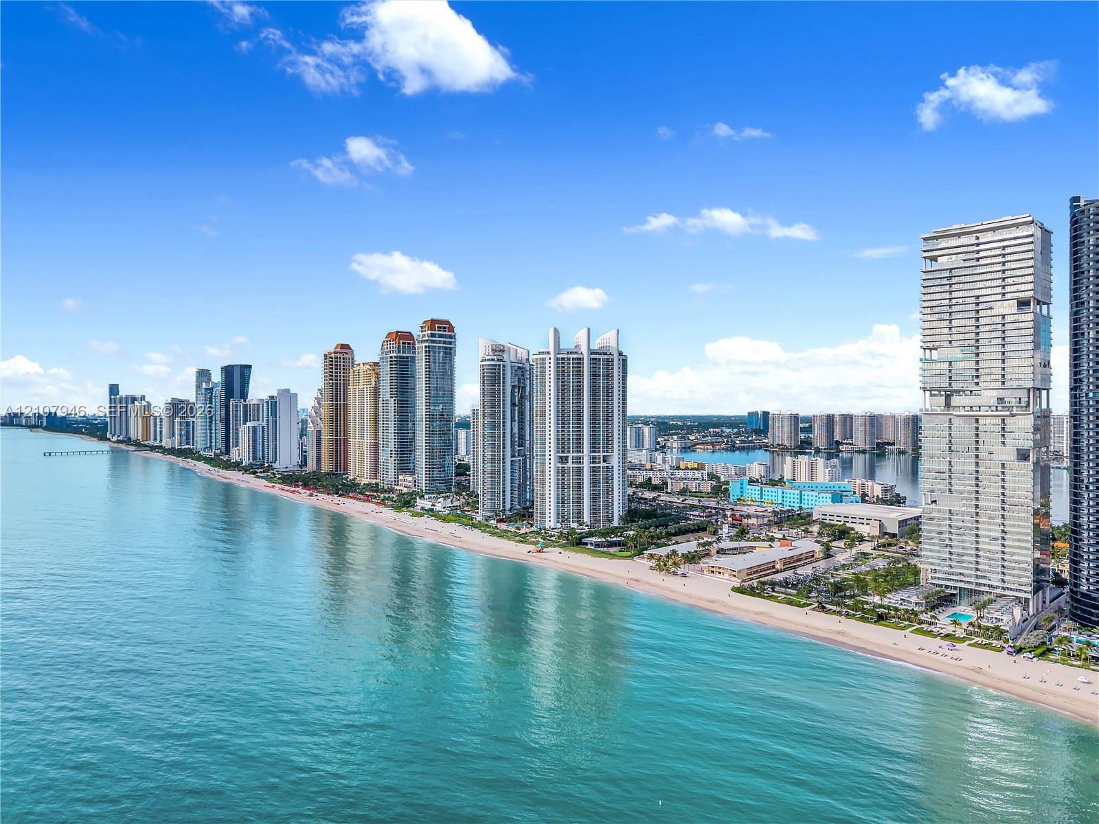 Aerial perspective featuring an extensive shoreline, coastal waters, and high-rise structures Aerial perspective featuring an extensive shoreline, coastal waters, and high-rise structures