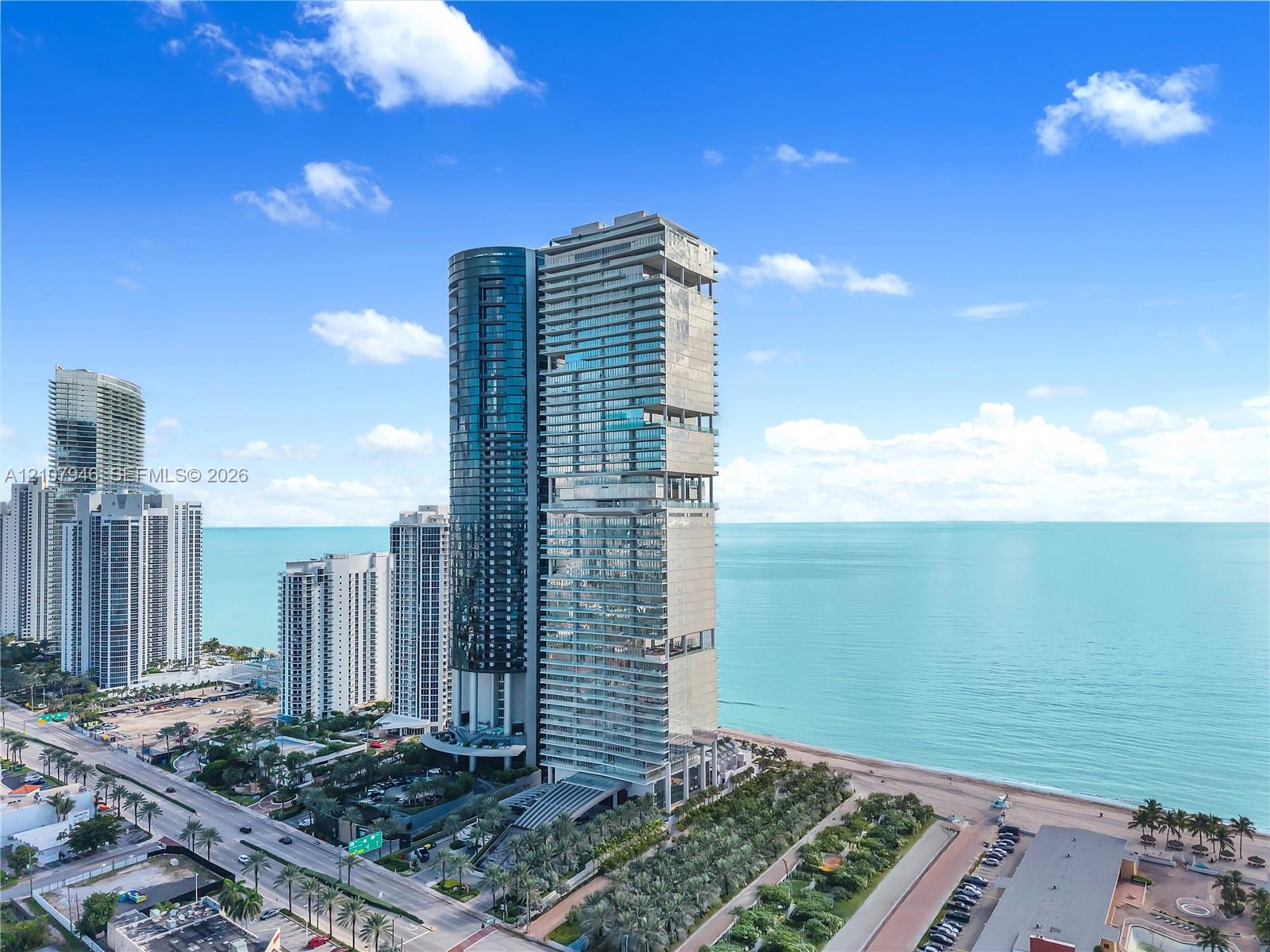 High-rise residential tower featuring a glass facade, recessed balconies, and direct proximity to the oceanfront