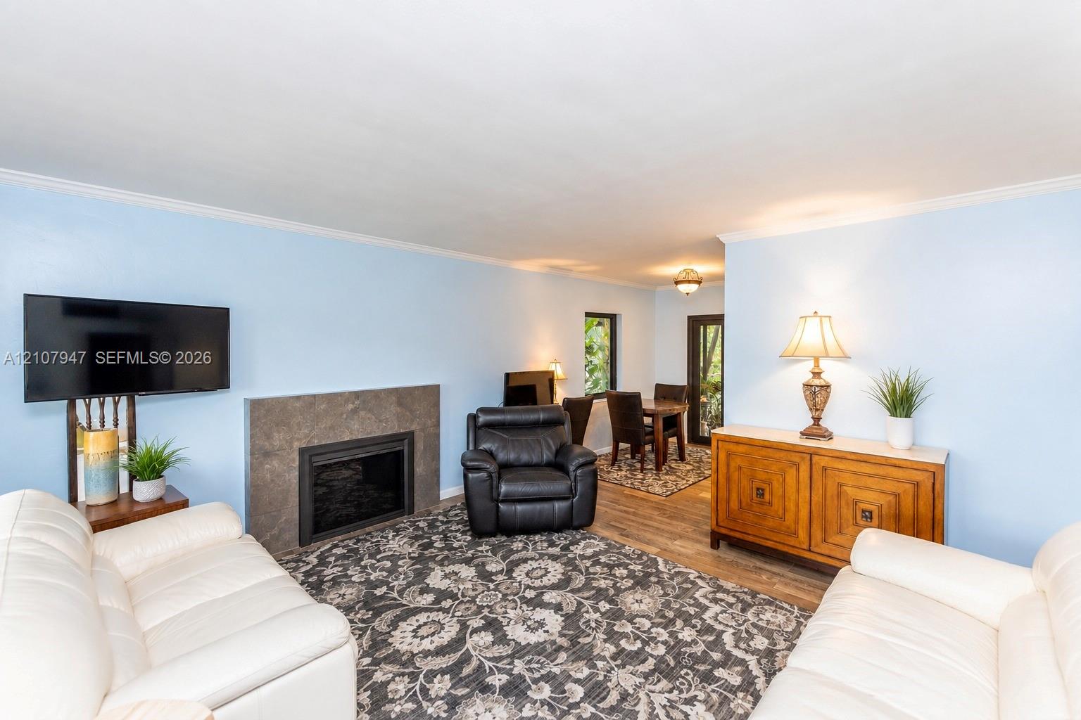 Living area featuring wood-finish flooring and a fireplace with a stone-finish surround Living area featuring wood-finish flooring and a fireplace with a stone-finish surround