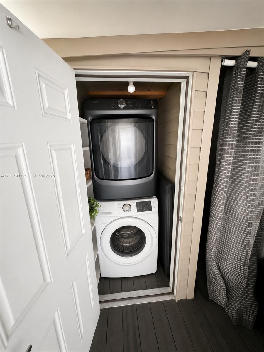 Laundry closet featuring stackable appliances, built-in shelving, and a white paneled door
