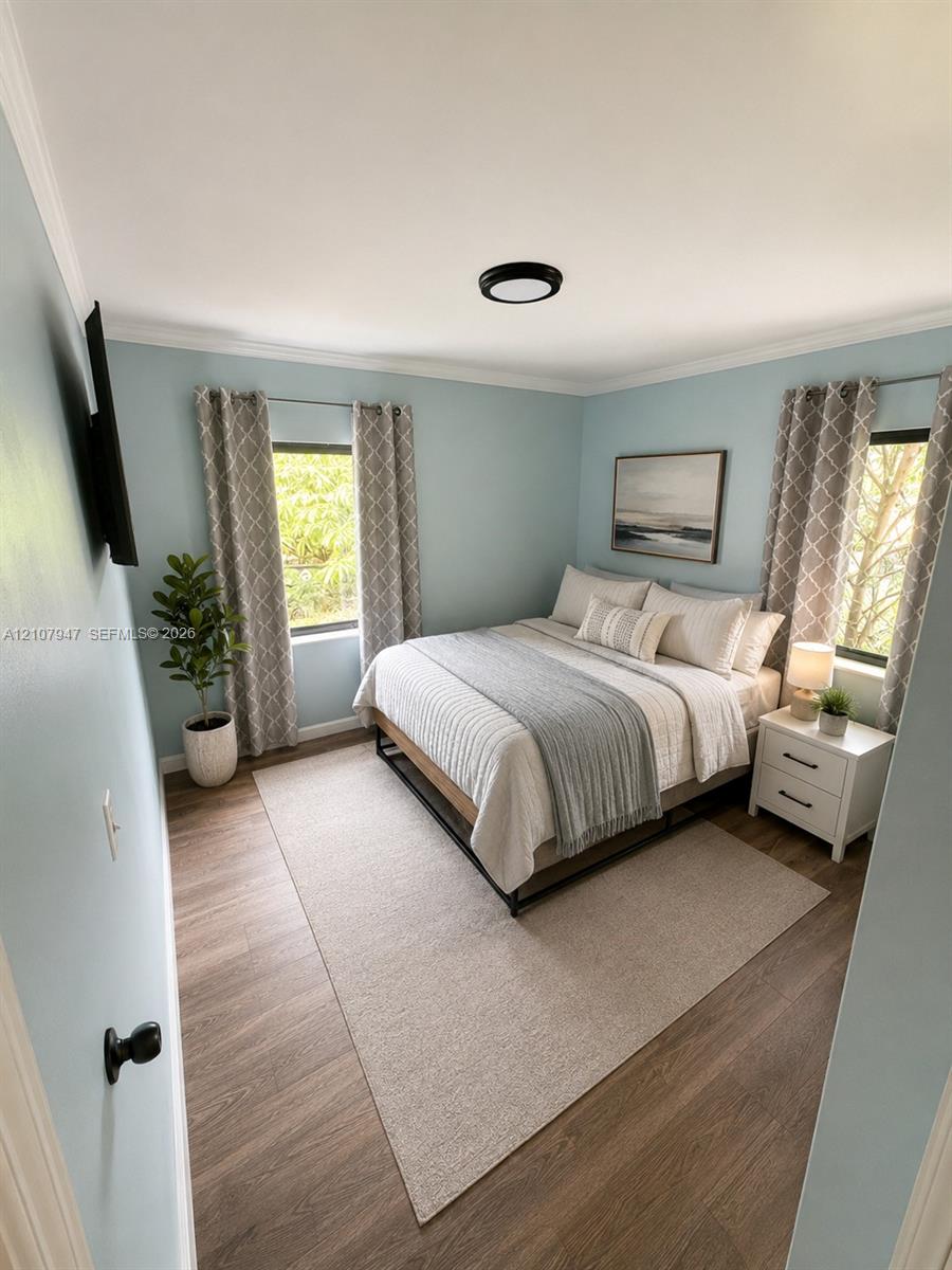 Room featuring wood-finish flooring, two windows, and a flush-mount ceiling light fixture Room featuring wood-finish flooring, two windows, and a flush-mount ceiling light fixture
