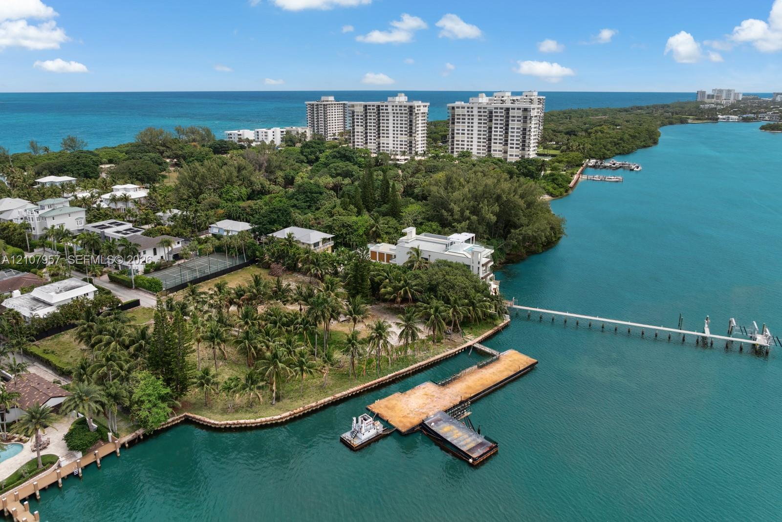 Waterfront property featuring extensive private shoreline, a large bulkhead-supported pier, and mature palms on a level lot