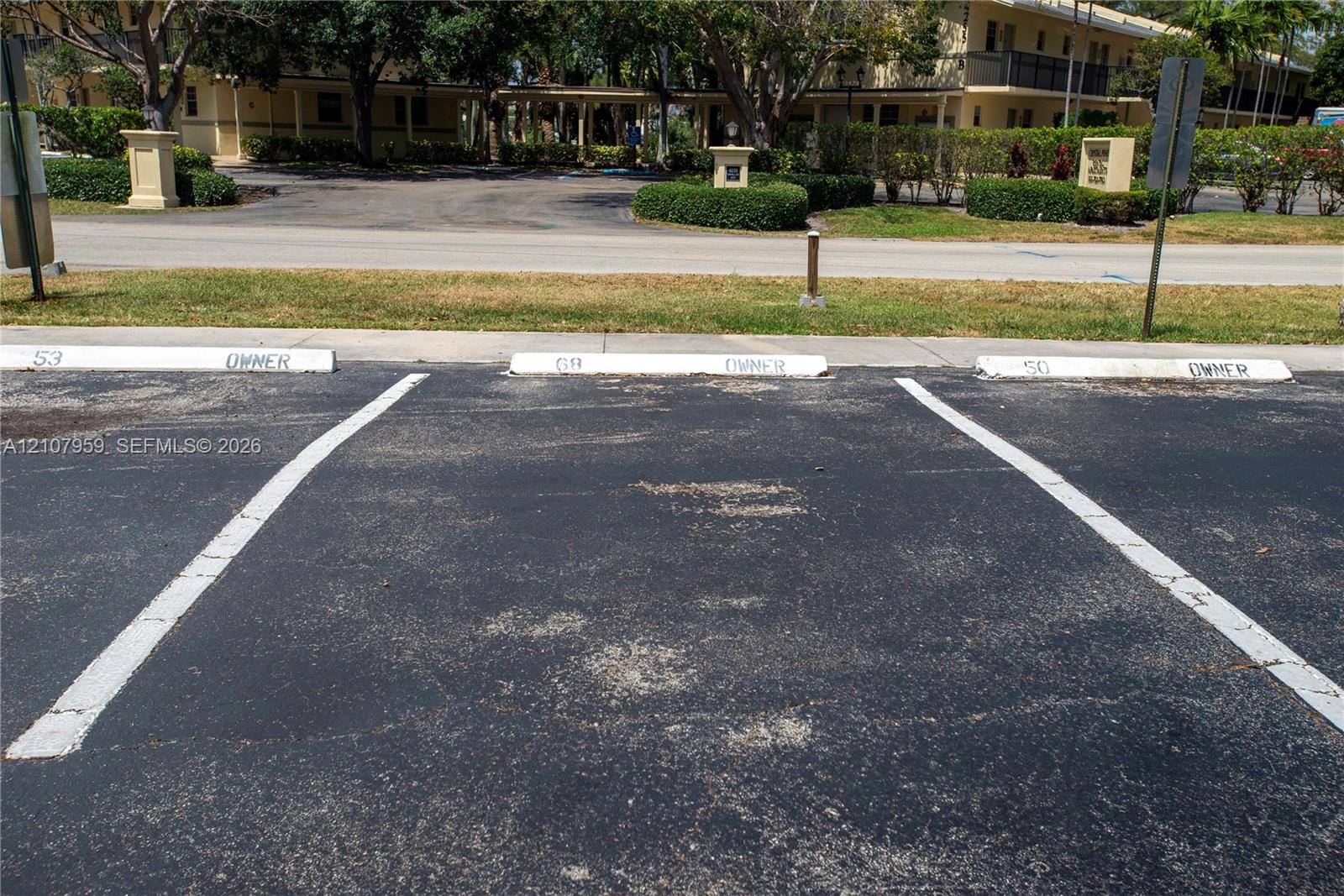 Asphalt parking area with three designated surface parking spaces and painted wheel stops