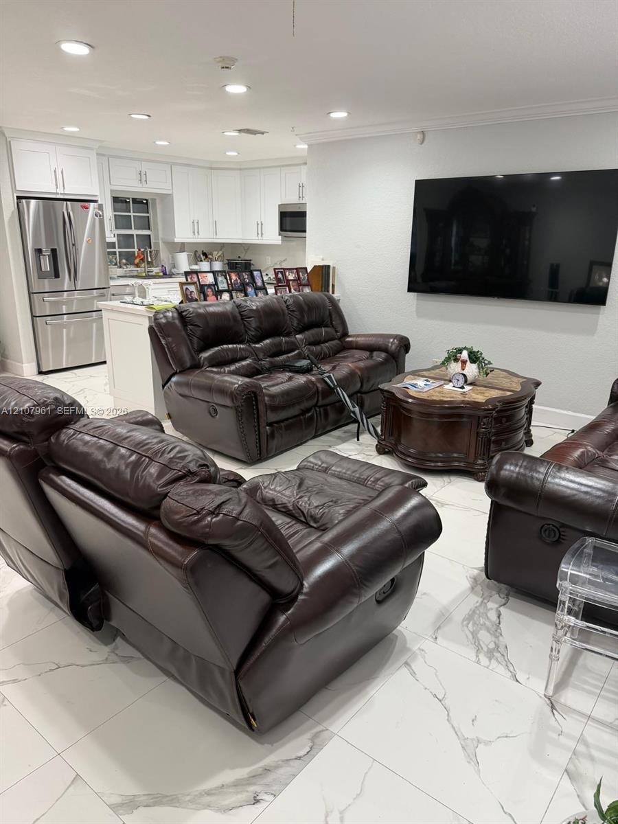 Open floor plan featuring white cabinetry, stone-finish tile flooring, recessed ceiling lighting, and stainless steel appliances