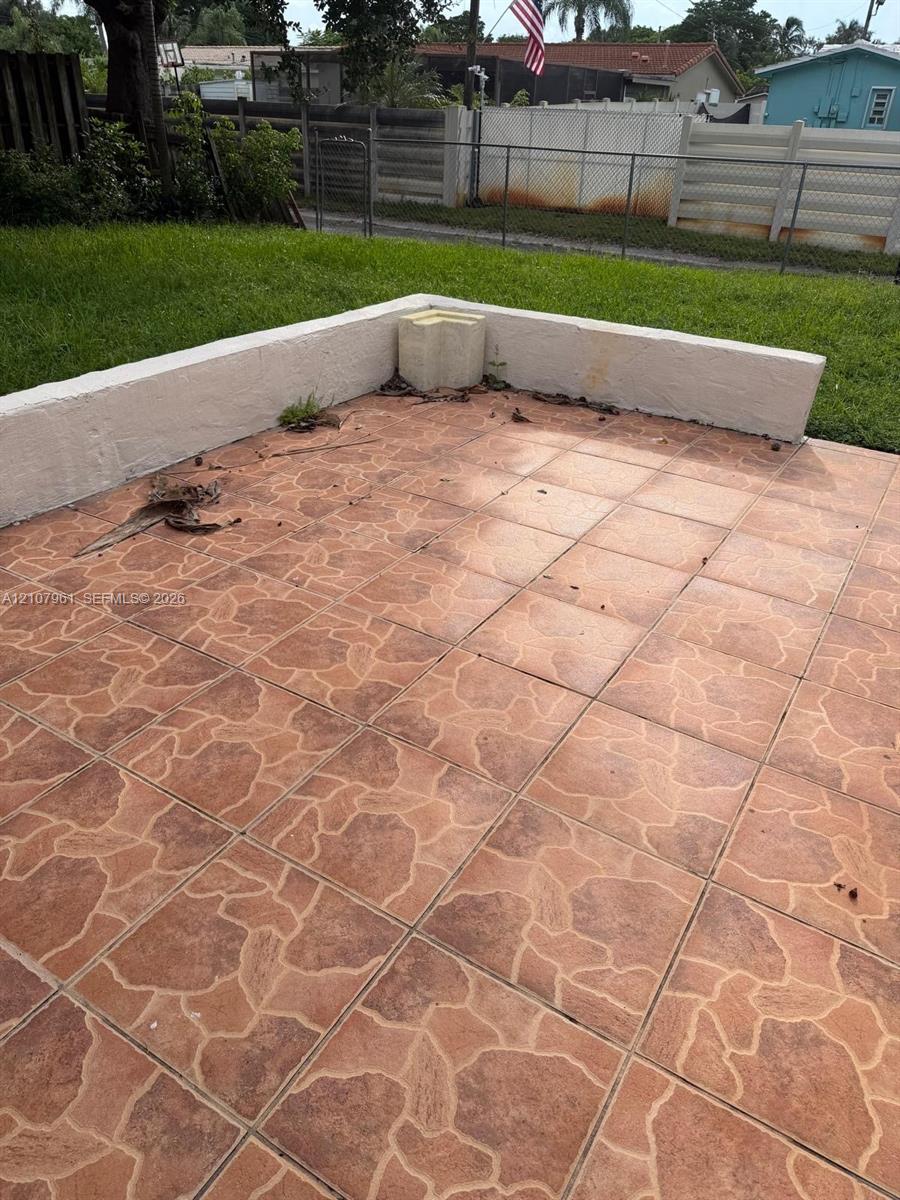 Tiled patio featuring a low-profile masonry retaining wall and manicured lawn