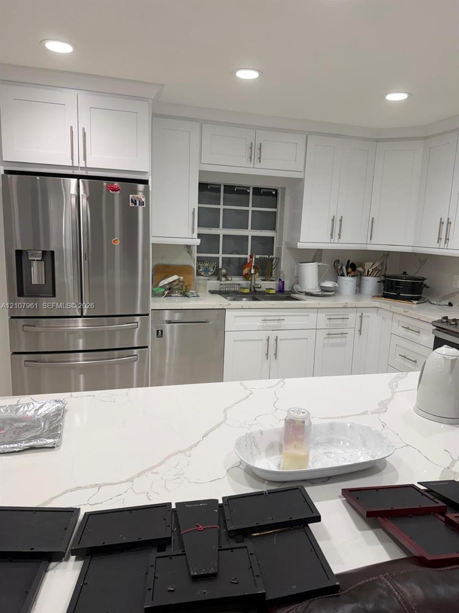 Kitchen featuring white shaker-style cabinetry, quartz countertops with veining, recessed lighting, and stainless steel appliances