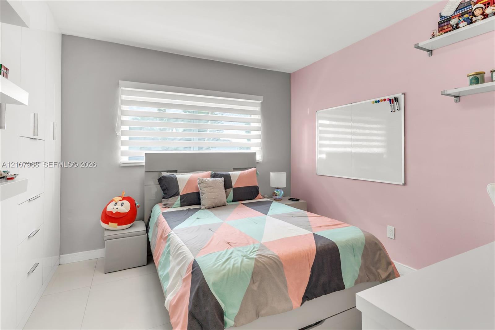 Built-in floor-to-ceiling white cabinetry, layered window blinds, and light-toned tile flooring
