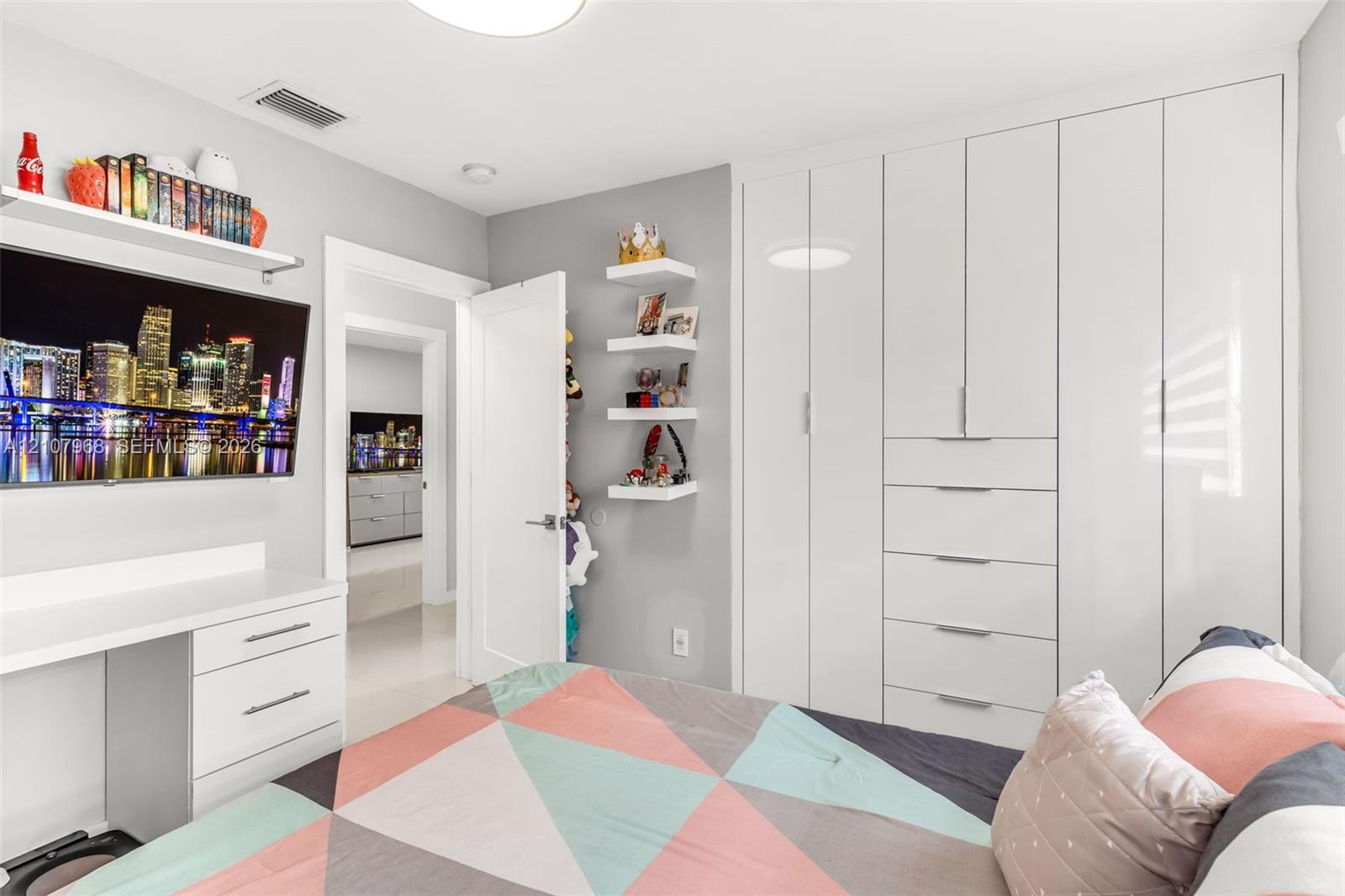Floor-to-ceiling white cabinetry featuring integrated drawer storage, built-in white desk with drawer storage, and wall-mounted white shelving