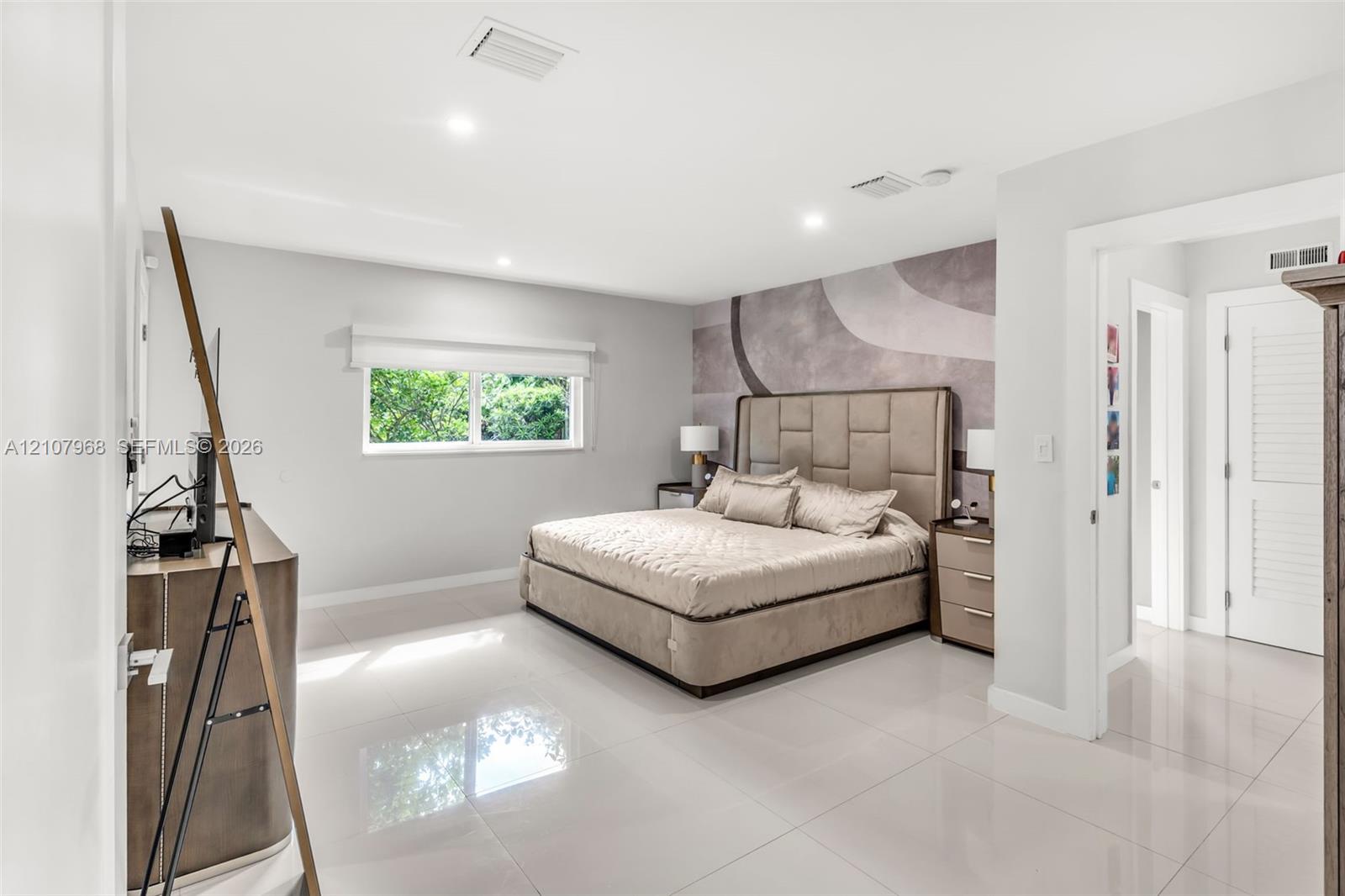 Spacious room featuring polished tile flooring, recessed lighting, and a large-format textured accent wall