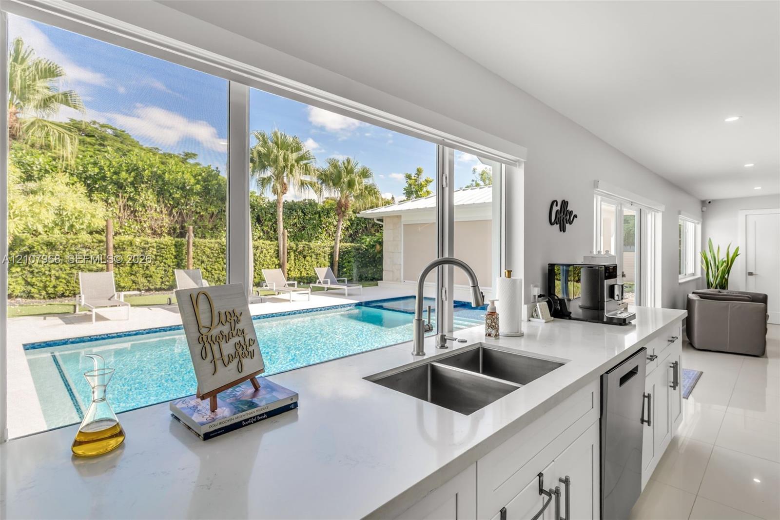 Kitchen featuring expansive windows, white cabinetry, quartz countertops, dual-basin stainless steel sink, and stainless steel dishwasher