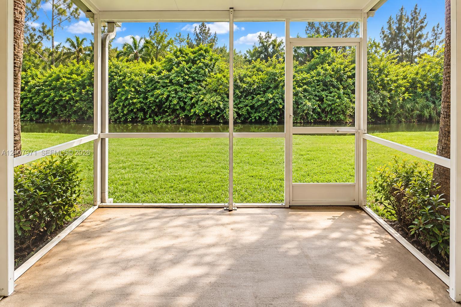 Screened-in patio with concrete flooring, aluminum framing, and a full-height entry door, overlooking a lawn and waterfront Screened-in patio with concrete flooring, aluminum framing, and a full-height entry door, overlooking a lawn and waterfront