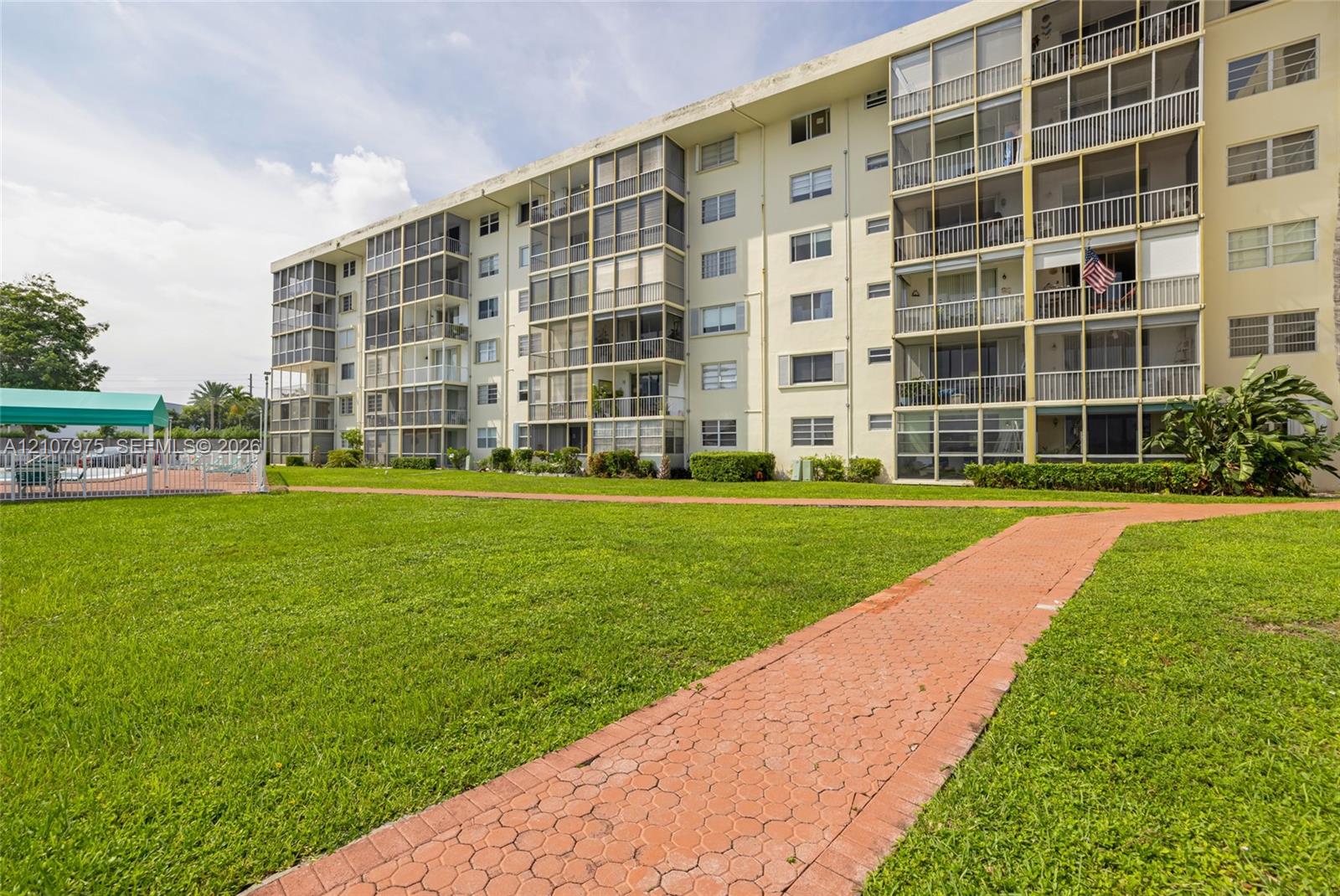 Multi-story building featuring screened balconies, landscaped grounds, and paved walkways