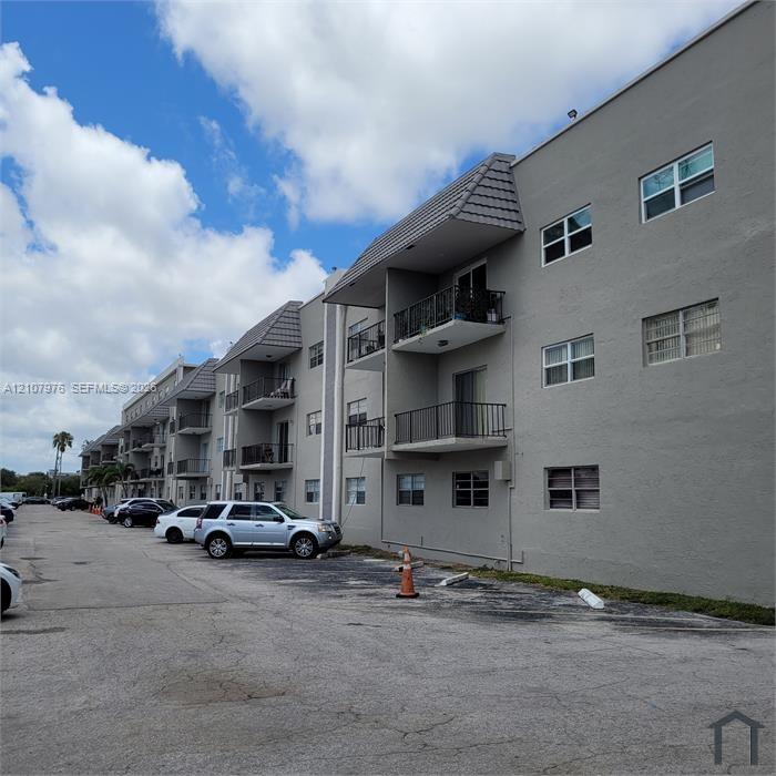 Multi-story stucco exterior featuring stacked metal-railed balconies and tiled roof accents