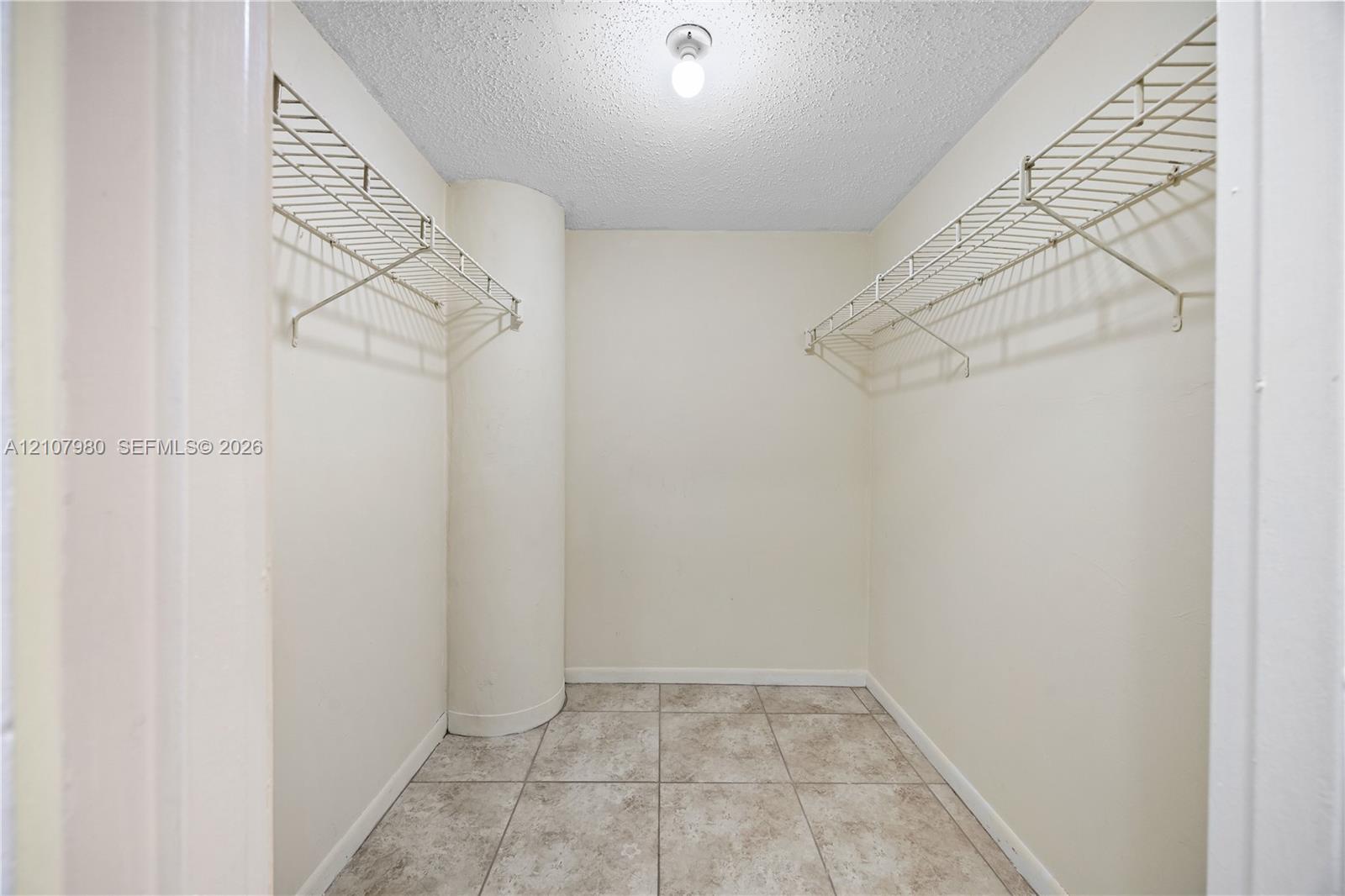 Storage area featuring tile flooring, dual-level wire shelving, and a singular ceiling-mounted light fixture