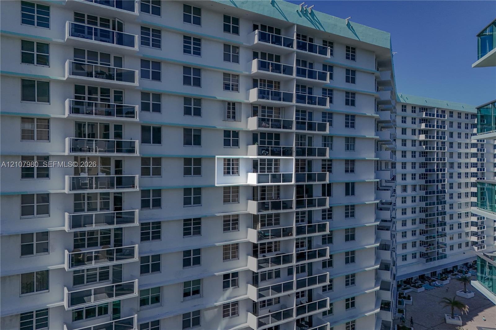 High-rise exterior featuring individual balconies with glass railings and white concrete structural facade