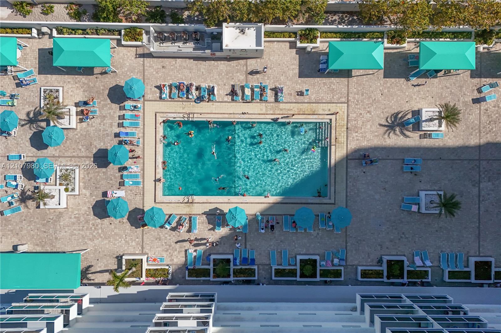 Rectangular swimming pool featuring tile surround, multiple built-in shade structures, paver decking, and integrated planters