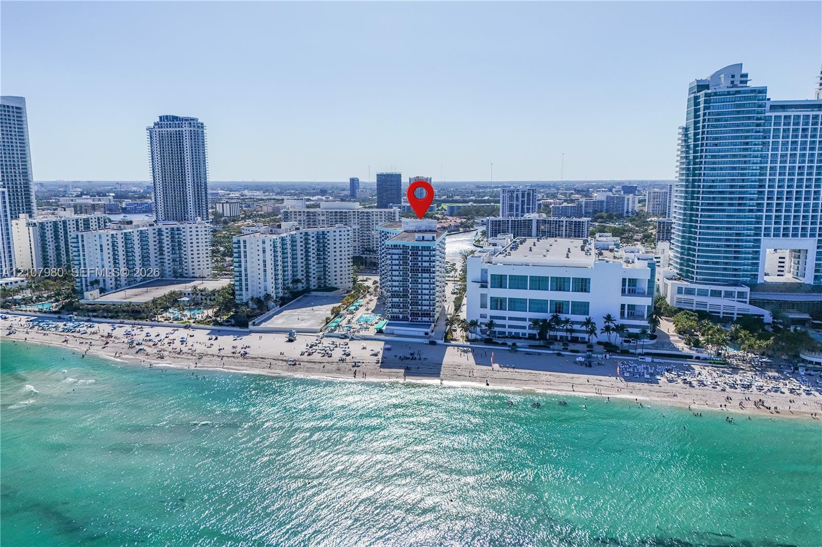 High-rise condominium exterior located directly on the coastline, featuring prominent ocean frontage and proximity to sandy beaches
