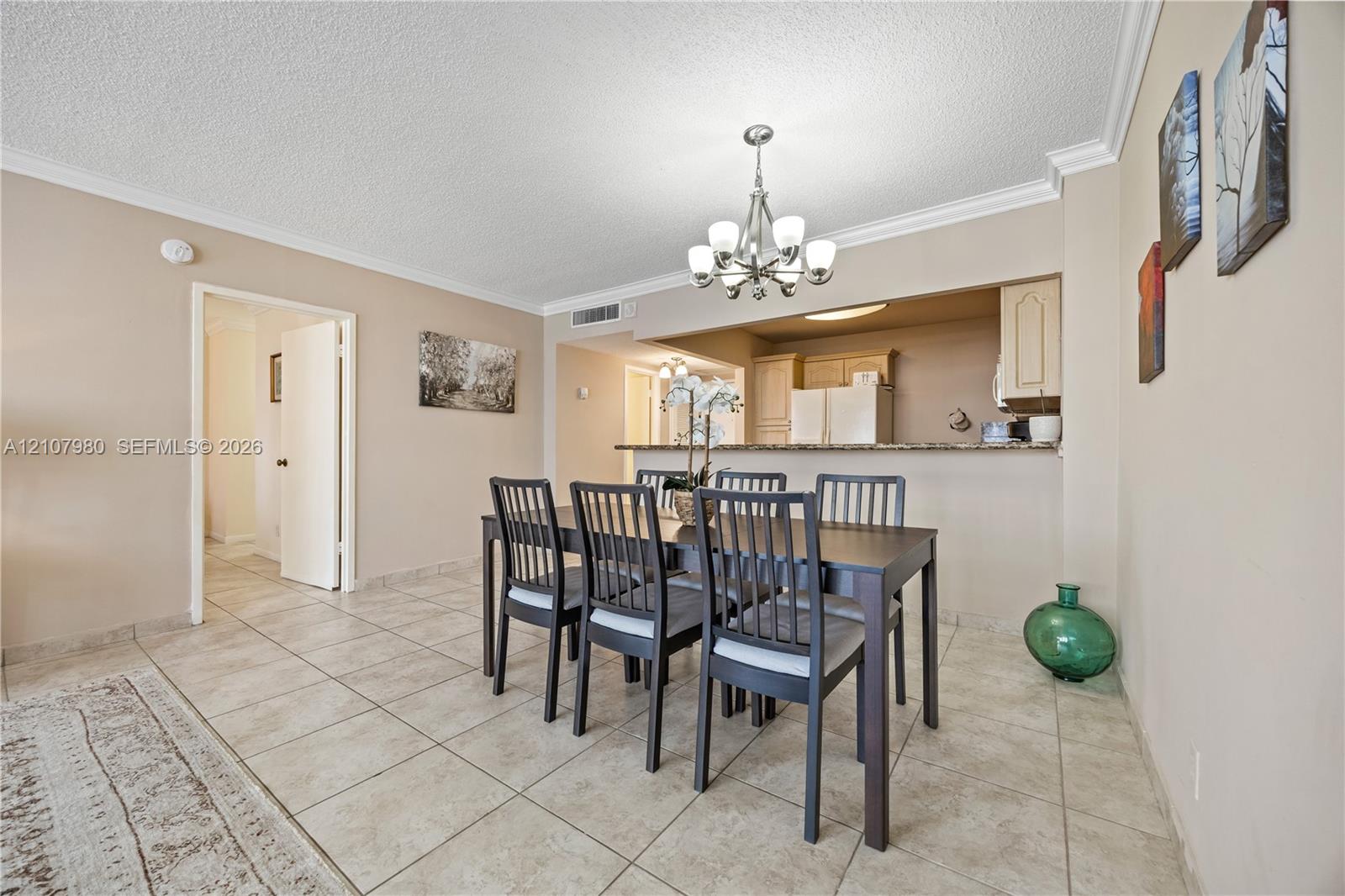 Dining area featuring neutral wall paint, tile flooring, crown molding, and an overhead multi-light chandelier