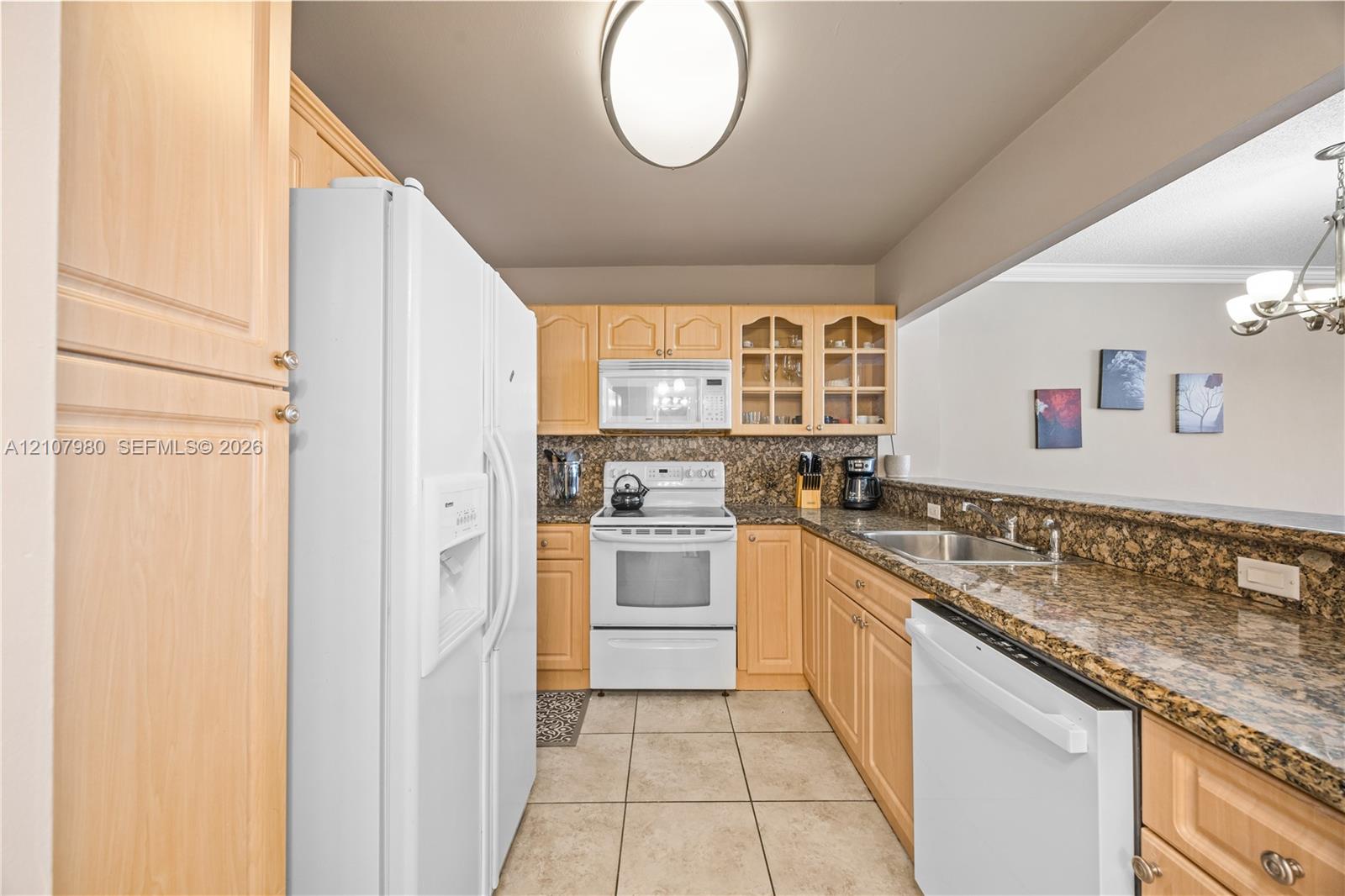 Kitchen featuring light-finish cabinetry, stone-finish countertops, ceramic tile flooring, built-in glass-front upper cabinets, and a pass-through opening