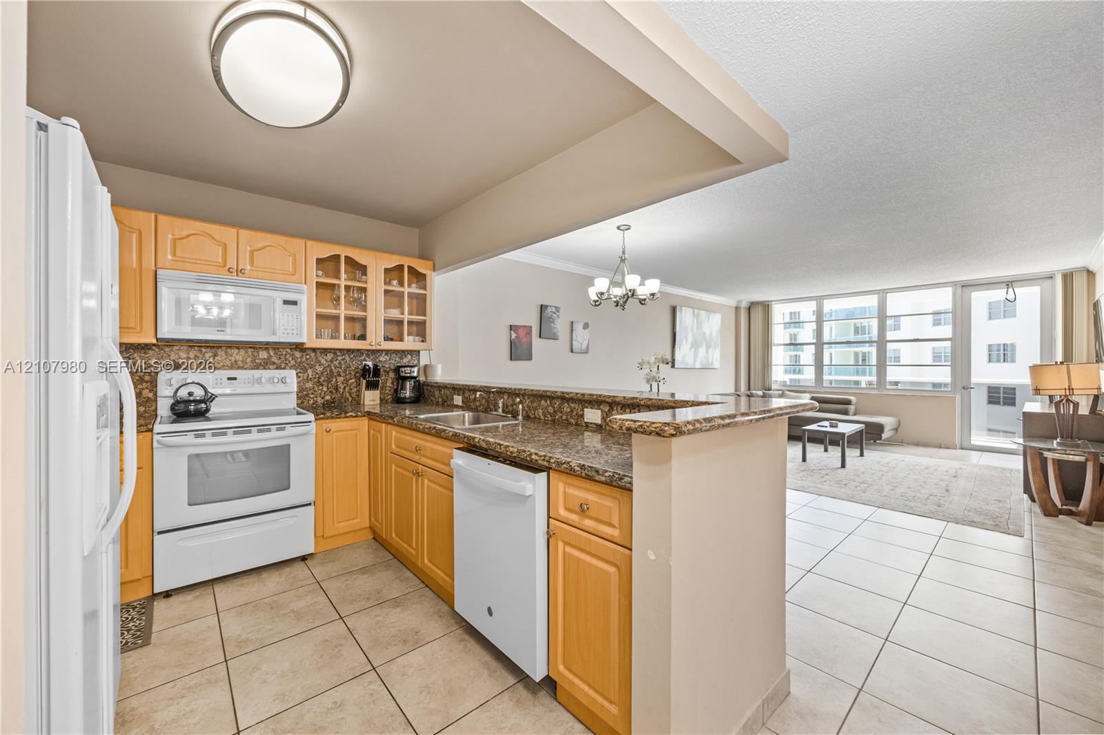Kitchen featuring natural finish cabinetry, stone-style countertops, white appliances, and tiled flooring