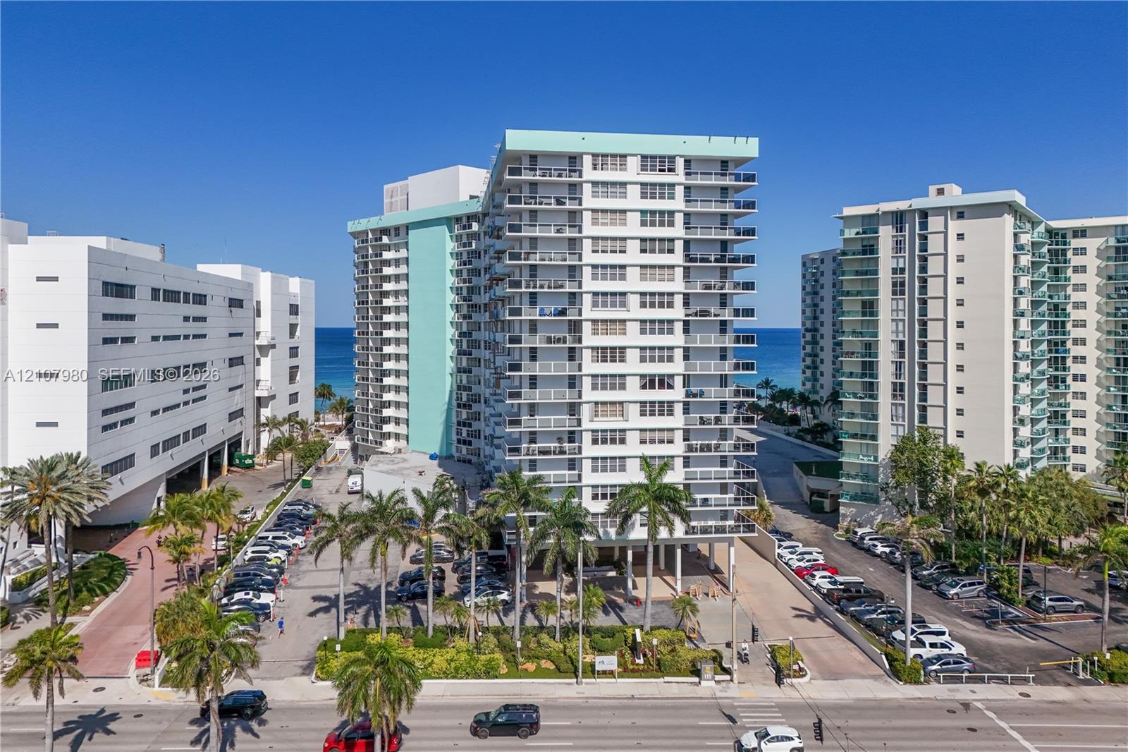High-rise multi-story building featuring private balconies, floor-to-ceiling glass doors, and mature palm tree landscaping