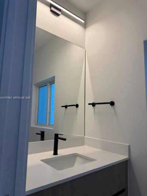 Wall-mounted linear LED lighting, large-format mirror, matte black faucet, integrated basin, and white solid-surface countertop
