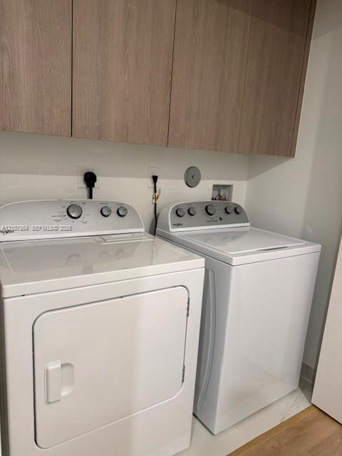 Laundry area featuring wood-finish cabinetry, white wall-mounted upper cabinets, and white stone-finish flooring Laundry area featuring wood-finish cabinetry, white wall-mounted upper cabinets, and white stone-finish flooring