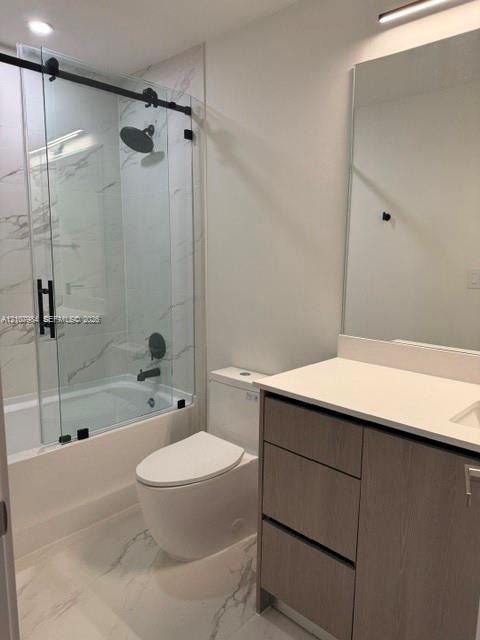 Bathroom featuring a sliding glass shower door with matte black hardware, rainfall showerhead, large-format tile flooring, vanity with a light-tone wood-finish cabinet, and a solid surface countertop