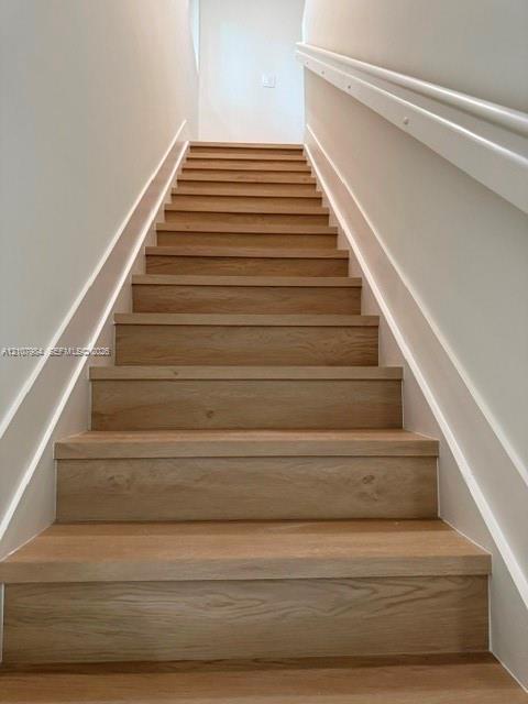 Staircase featuring wood-finish treads and white painted handrails