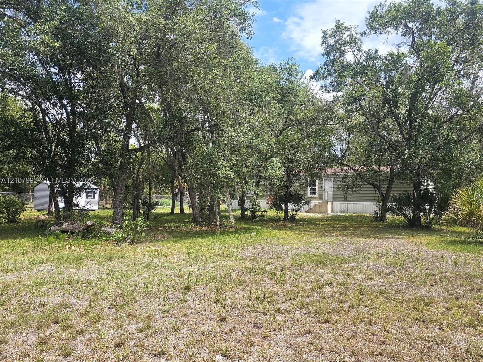 Expansive lot featuring mature trees, natural vegetation, a detached storage structure, and horizontal exterior siding Expansive lot featuring mature trees, natural vegetation, a detached storage structure, and horizontal exterior siding