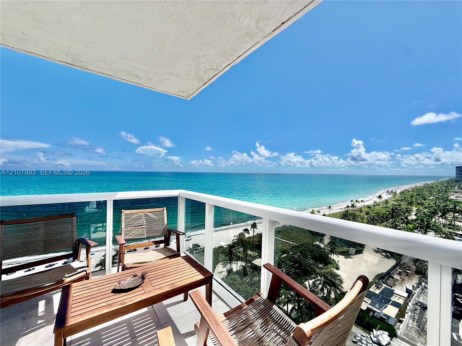 Private balcony featuring a glass-panel railing, overhead covering, and concrete flooring, overlooking the coastline and ocean